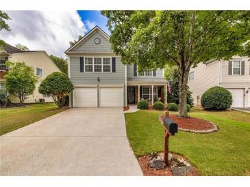 Two-story house with gray siding, two-car garage, and landscaped yard at 207 Persimmon Trl, Woodstock, GA 30188