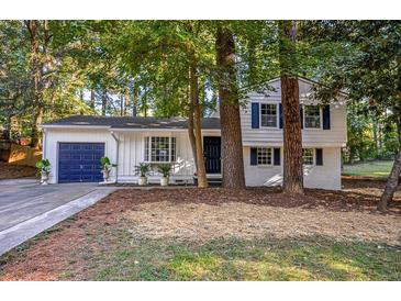 Charming white two-story home nestled among trees with a blue garage door at 4001 Red Oak Dr, Atlanta, GA 30340