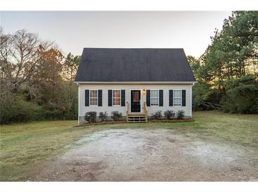 Beige house with black shutters, a gray roof, and a small yard at 4948 Emmett Still Rd, Loganville, GA 30052