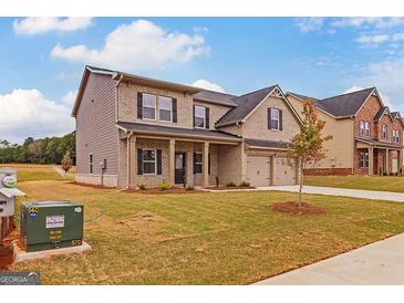 Two-story home with brick exterior, front yard landscaping, and attached two-car garage at 1628 Fuma Leaf Way, Mcdonough, GA 30253