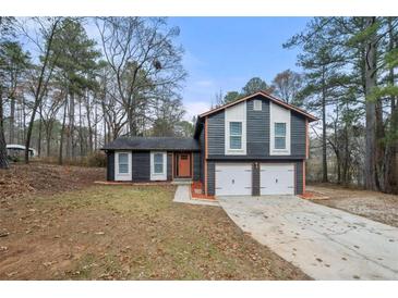 Ranch style home with gray siding, two-car garage, and landscaped yard at 5404 Winslow Xing, Lithonia, GA 30038