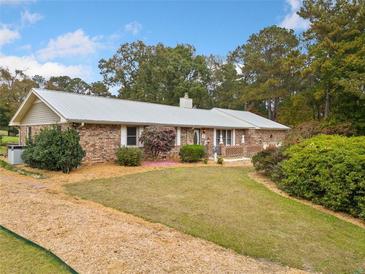 Brick ranch house with a metal roof, landscaping, and a large yard at 7312 Melrose Ct, Villa Rica, GA 30180