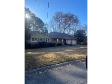Ranch style home with a green exterior, large yard, and attached garage at 3262 Carriage Way, Marietta, GA 30062
