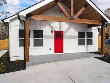 White farmhouse exterior with a red door, wood beams, and a covered porch at 860 Gardner Sw St, Austell, GA 30168