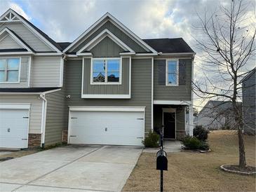 Two-story townhome with gray siding, white garage door, and landscaping at 3885 Nixon Grove Dr, Douglasville, GA 30135