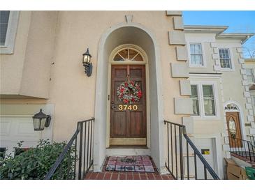 Tan three-story townhouse with a white garage door and brick steps leading to the entrance at 3740 Meeting Nw St, Duluth, GA 30096