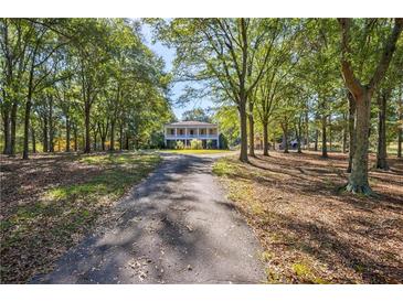 Long driveway leading to a charming two-story home nestled among lush trees at 1490 Lee Peters Rd, Loganville, GA 30052
