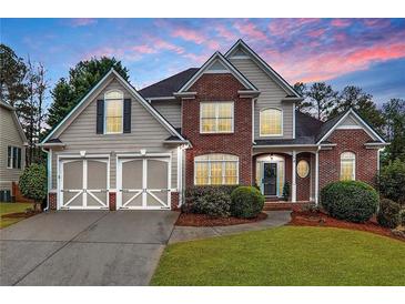 Brick two-story house with a three-car garage and landscaped yard at 67 Vine Creek Pl, Acworth, GA 30101