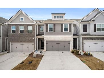 Two-story townhome with gray siding, two-car garage, and landscaping at 7757 Squire Ct, Fairburn, GA 30213