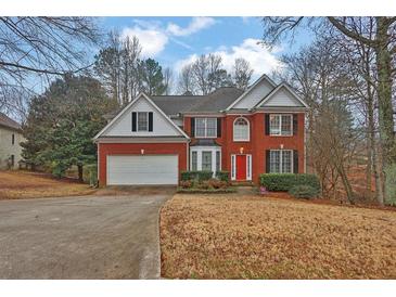 Brick two-story house with a white garage door and landscaping at 625 Piping Rock Pt, Lawrenceville, GA 30043