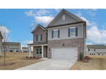 Two story home with gray siding and brick accents, two car garage, and a landscaped yard at 608 Somerset Ct, Loganville, GA 30052