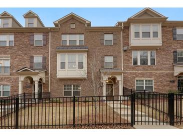 Brick front exterior of townhome with a black metal fence and landscaping at 2065 Morrison Ave, Brookhaven, GA 30319