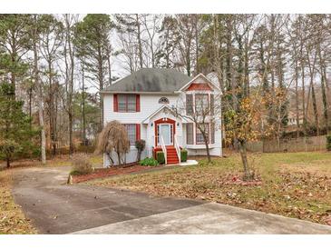 Two-story house with red accents, driveway, and mature trees in the yard at 308 Mainsail Ln, Woodstock, GA 30189