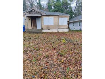 Fixer-upper house with boarded windows and yard at 1409 Mims St, Atlanta, GA 30314