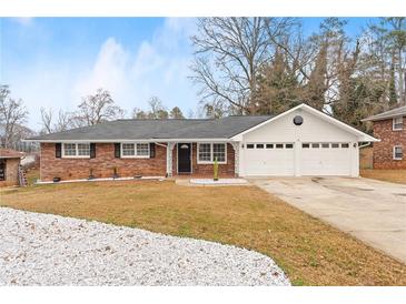 Brick ranch house with a two-car garage and landscaped yard at 1283 Woodleigh Sw Rd, Marietta, GA 30008