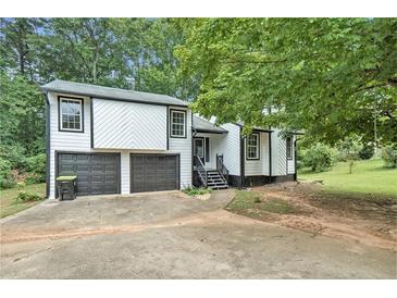 White two-story house with black accents, two-car garage, and landscaping at 2940 Leah Ln, Douglasville, GA 30135