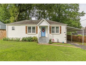 Charming white brick ranch home with a blue door, landscaped lawn, and carport at 723 Campbell Cir, Hapeville, GA 30354