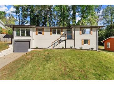 Newly renovated ranch home with a modern gray and white exterior, landscaped lawn, and attached garage at 3524 Brookfield Ln, Decatur, GA 30032