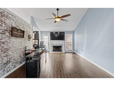 Spacious living room featuring hardwood floors, fireplace, and brick accent wall at 3321 Caleb Sw Rd, Snellville, GA 30039