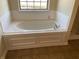 Oval bathtub with tile surround and neutral colored flooring at 7495 St David St, Fairburn, GA 30213