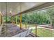 Large covered porch with stone patio, wooden swing, and view of wooded area at 2752 Poplar Rd, Sharpsburg, GA 30277