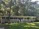 Ranch home with gray brick exterior, white trim, and a red front door, nestled amongst lush green trees at 3207 Cloverhurst Dr, East Point, GA 30344