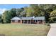 Brick ranch home with a covered porch, well-manicured lawn, and wooded backdrop at 138 Michelle Dr, Mcdonough, GA 30252