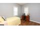 Cozy bedroom featuring a yellow bedspread, a workspace, and two windows at 112 Parson St, Bowdon, GA 30108