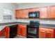 Kitchen with dark wood cabinets, black appliances, and corner sink at 2384 Coach Way, Jonesboro, GA 30236