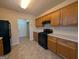 Galley kitchen with wood cabinets, black appliances, and tiled floor at 6195 Winston Trce, Mcdonough, GA 30252