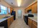 Galley kitchen with wood cabinets, black appliances, and tiled floor at 6195 Winston Trce, Mcdonough, GA 30252