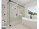 Modern bathroom featuring a glass-enclosed shower and a soaking tub by a bright window at 3920 Clifton Hill Ct, Cumming, GA 30040
