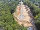 Aerial view of a construction area with a newly paved street winding through wooded and cleared land at 3920 Clifton Hill Ct, Cumming, GA 30040