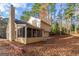 Backyard view of a two-story home with a screened porch, chimney, and wooded area at 138 Rockspray Ridge, Peachtree City, GA 30269