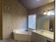 Main bathroom featuring corner tub, dual vanity, and patterned walls at 3003 Canter Way, Duluth, GA 30097