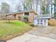 Brick home with a unique design, featuring an outdoor deck, shed, and mature trees at 562 Dickens Nw Rd, Lilburn, GA 30047