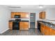 Kitchen with wood cabinets, black appliances, and dark flooring at 30 Capeton Ct, Covington, GA 30016