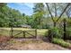 Wooden gate entrance to a large grassy area with trees at 1827 Lost Mountain Rd, Powder Springs, GA 30127