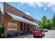 Brick building with outdoor seating and a metal awning; Blue Eyed Daisy BakShop at 9032 Selborne Ln, Chattahoochee Hills, GA 30268