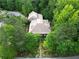 Aerial view of house nestled in woods with landscaped gardens at 9170 Selborne Ln, Chattahoochee Hills, GA 30268