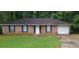 Brick ranch house with a garage and a grassy yard at 1967 Singer Way, Lithonia, GA 30058