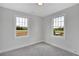Bright bedroom with two windows offering ample natural light and gray carpeting at 1356 Flora Dr, Conyers, GA 30094