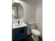 Small bathroom with blue vanity, white toilet, and octagon mirror at 4604 Shumart Dr, Snellville, GA 30039