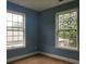 Empty bedroom with blue walls, brown carpet, and two windows at 2159 Martin Luther King, Jr. Dr, Atlanta, GA 30310