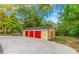 Three-car detached garage with red doors and large concrete driveway at 1068 N Main Nw St, Conyers, GA 30012