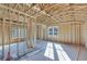 Framed room with exposed wooden beams and studs. Sunlight streams through the window at 1264 Six Sisters St, Dacula, GA 30019
