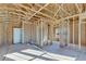 A framed room with wooden beams, studs, and a white door, illuminated by natural light at 1264 Six Sisters St, Dacula, GA 30019