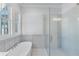 Modern bathroom with a soaking tub, glass shower, large window, and gray tile flooring at 1274 Six Sisters St, Dacula, GA 30019