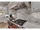 White kitchen features a professional range, marble backsplash and custom cabinetry at 962 Chattooga Trce, Suwanee, GA 30024