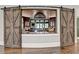 Home bar with barn doors, granite countertop and custom cabinetry at 962 Chattooga Trce, Suwanee, GA 30024